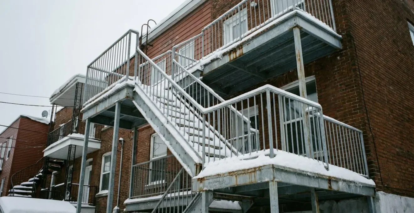 Escalier extérieur en acier galvanisé à Montréal recouvert de neige, vue documentaire d'une façade résidentielle en hiver